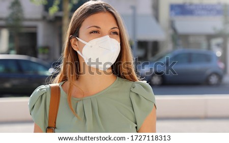 COVID-19 Pandemic Coronavirus Woman in city street wearing KN95 FFP2 mask protective for spreading of disease virus SARS-CoV-2. Girl with protective mask on face against Coronavirus Disease 2019.