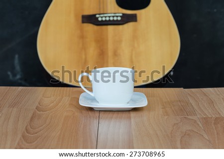 Cup of coffee on wooden and guitar background