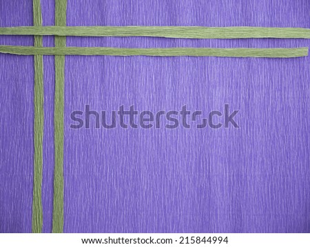 A blue crepe paper background with 2 green vertical lines crossing 2 other green horizontal lines at a corner