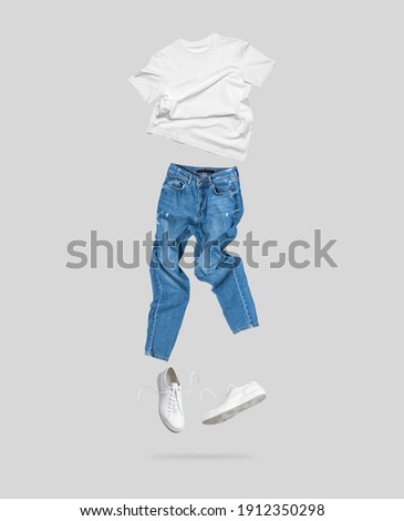 White flying cotton T-shirt, blue jeans, white leather sneakers isolated on gray background. Clean white Unisex T-shirt. Branding clothes. Mock up for your design. Spring Summer Women's Clothing