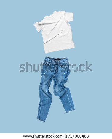 White flying cotton T-shirt, blue jeans isolated on blue background. Clean white Unisex T-shirt. Branding clothes. Mock up for your design. Spring Summer Women's Clothing. Classic White Basic T-shirt Foto stock © 
