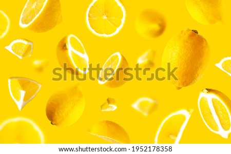 Juicy ripe flying lemons on yellow background. Creative food concept. Tropical organic fruit, citrus, vitamin C. Lemon whole and sliced. Summer minimalistic bright fruit background. Lemon pattern