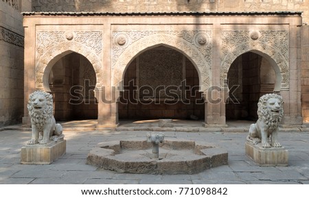 Two white marble lions statues and decorative fountain in front of three adjacent decorated stone arches at the garden of Manial Palace of Prince Mohammed Ali located in Manial district, Cairo, Egypt