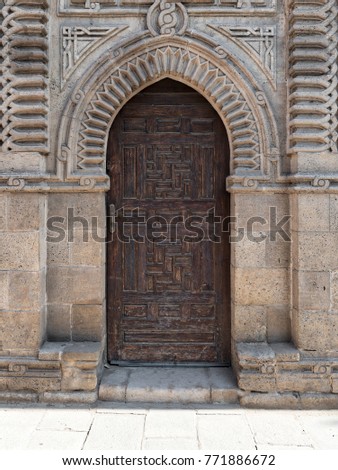 Grunge wooden ornate aged vaulted arched door on exterior decorated stone bricks wall at Manial Palace of prince Mohamed Ali, Medieval Cairo, Egypt