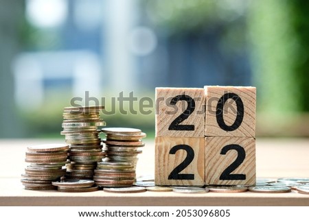 2022 NEW YEAR Business and saving money concept. Coins stack and wooden blocks number 2022 on blur background.