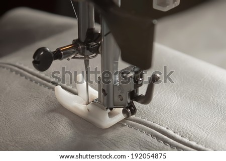 sewing machine needle and gray  leather with seam