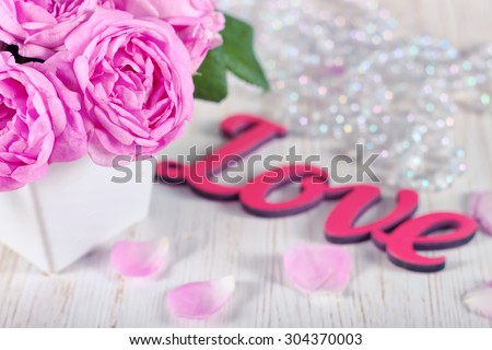 Pink roses and petals on wooden desk and red wooden word love. filtered in cold tone