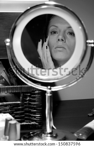 Model make-up in a round highlighted mirror, back & white