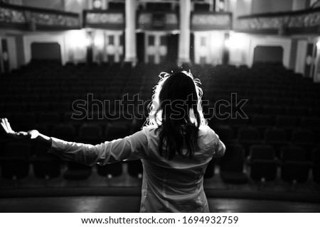 Entertainer performing on a stage in a empty theater,concert hall without fans.No audience.COVID-19 canceled show.Opera house without spectators.Playing to empty seats.Actor/singer entertaining no one