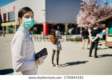 Shopper with mask standing in line  to buy groceries due to coronavirus pandemic in grocery store.COVID-19 shopping safety measures,social distancing.Quarantine preparation.Panic buying.Long queue