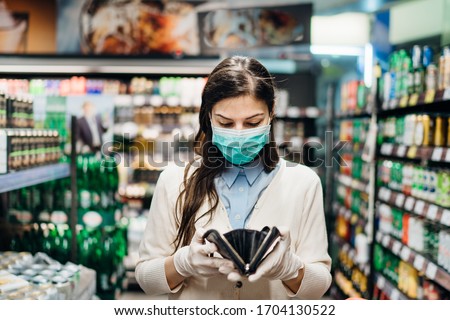 Worried woman with mask groceries shopping in supermarket looking at empty wallet.Not enough money to buy food.Covid-19 quarantine lockdown.Financial problems anxiety.Unemployed person in money crisis