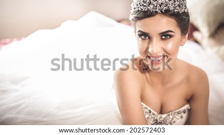 Gorgeous bride portrait in her wedding dress wearing tiara. Beautiful bridal makeup and hairstyle and hair accessories. Bride to be smiling portrait