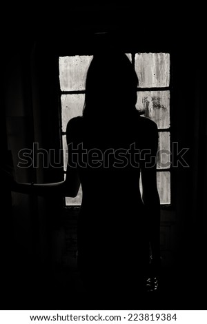 Woman silhouette with dirty old window in the background