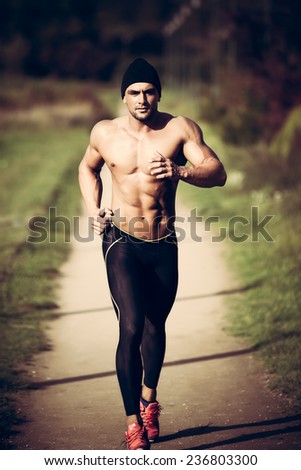 Handsome strong muscular athletic man working out and running outdoors in nature