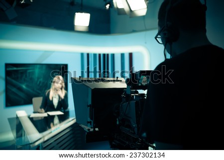 Young beautiful blonde television announcer at studio during live broadcasting.Female TV director at editor in studio.Recording at TV studio with television anchorwoman. TV NEWS studio with camera