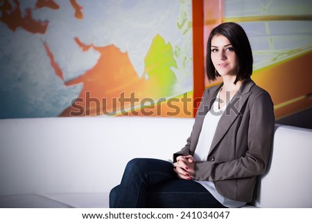 Young beautiful brunette television announcer at studio during live broadcasting.Female TV director at editor in studio.Recording at TV studio with television anchorwoman. TV NEWS studio