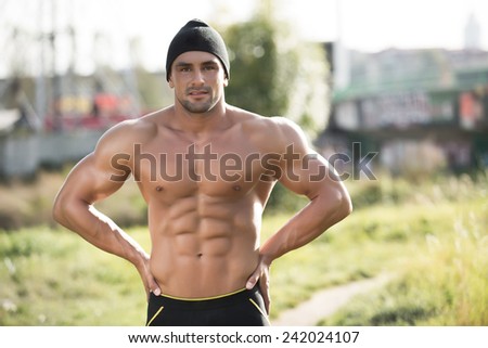 Handsome strong muscular athletic man after working out outdoors in nature