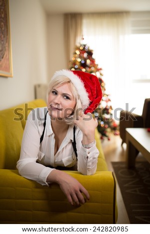 Christmas Santa hat woman portrait with Christmas tree.Smiling happy girl in Santa hat. Happy Christmas and New Year.Sexy seductive woman wearing her Santa hat in warm cozy home