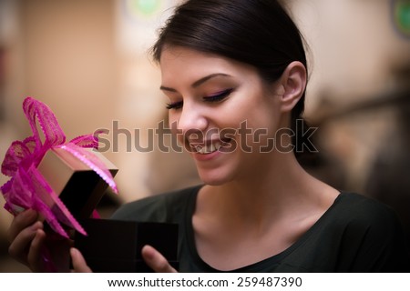 Happy girl surprised opening a gift box.Holidays,celebrations and people concept - smiling woman holding and opening present from a dear person,boyfriend or husband.Woman \'s hands unpacking a present