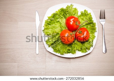 Fitness concept with healthy dieting and healthy lifestyle.Concept of diet,health and nutrition.Vibrant colorful vegetables on plate.Eating salad.Bright red tomatoes and lettuce diet meal