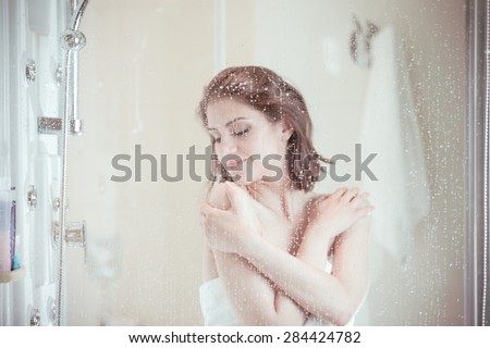 Relief and relaxation after long stressful day.Taking moment for yourself concept.Skincare,spa and aromatherapy.Unfocused portrait of a woman showering through the bath screen with little drops