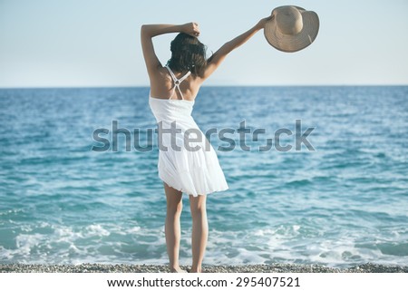 Beautiful woman in a white dress walking on the beach.Relaxed woman breathing fresh air,emotional sensual woman near the sea, enjoying summer.Travel and vacation. Freedom and inspiration concept
