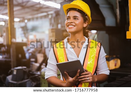 Industry maintenance engineer woman dark skin wearing uniform and safety helmet under inspection and checking production process on factory station by tablet. Industry, Engineer, construction concept.