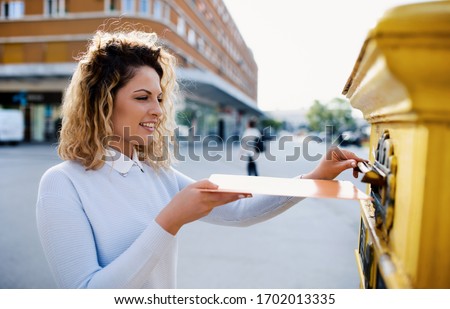 Smiling woman sending a letter and documents via mailbox. Business, lifestyle concept