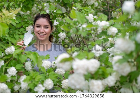 Happy red-haired woman takes off a medical mask while standing next to a blossoming apple tree in a park. Ending seasonal allergic rhinitis. The girl was cured of an allergy to pollen. Zdjęcia stock © 