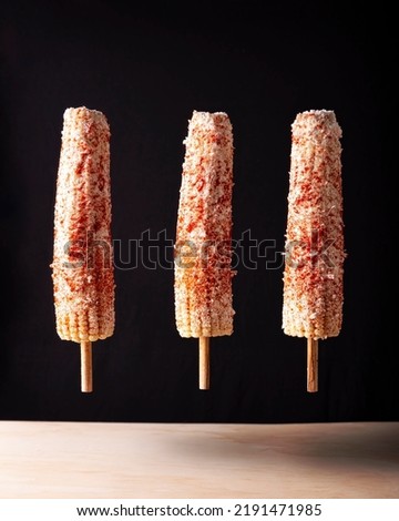 Elotes Callejeros are a popular street snack in Mexico, it is tender corn cooked with spices, skewered on a wooden stick covered with mayonnaise or sour cream, fresh cheese and piquin chili powder. Foto stock © 