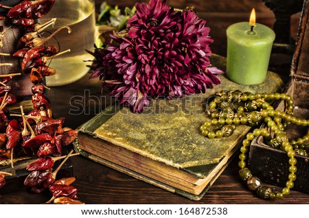 old book, flower, candle and open jewelry box with green necklace still life, renaissance concept with dark grunge light