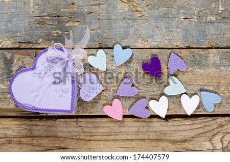 Heart shaped Valentines Day present gift box with small hearts around it on old wood.