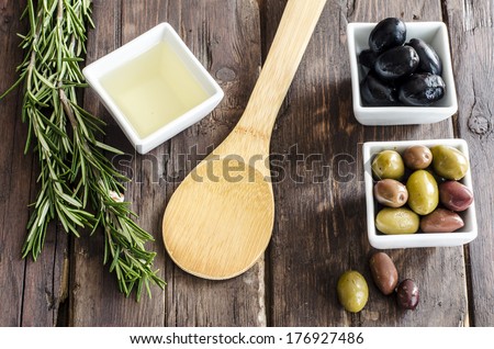 Bowl filled with fresh olives, olive oil and herbs on a rustic wooden tabletop