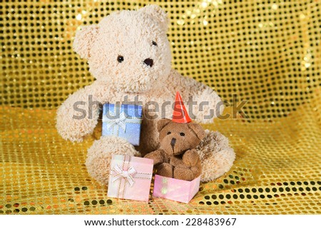 teddy bear toy on gold glitter background with gift box