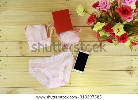 pink underwear and red box with smart phone near roses on wood floor