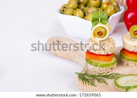 finger foods made of bread, peppers, cucumber cheese and olives on white wooden table
