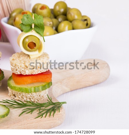 finger foods made of bread, peppers, cucumber cheese and olives on white wooden table