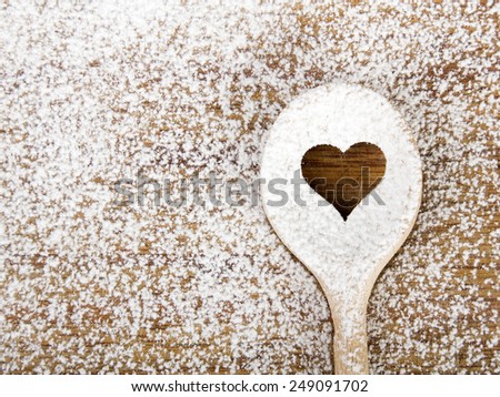 Heart hole spoon on the wooden pastry board - baking background