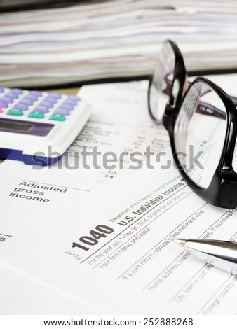 Close up U.S. Individual tax form 1040 with glasses, calculator and pen.