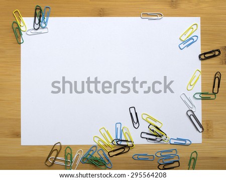 paper clips and blank paper on wooden background
