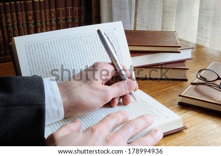 man with pen in hand looking for references in a book