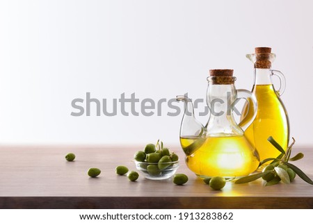 Olive oil in two glass containers and harvest olives on the wooden bench white isolated background. Front view. Horizontal composition.