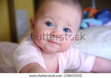 Female baby with pink body on the bed with direct gaze