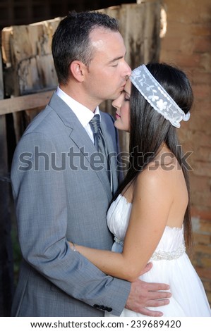 Groom giving gentle kiss on the forehead to the bride in a warehouse in ruins