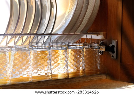 Clean dishes and glasses in the draining of a kitchen cabinet brown house
