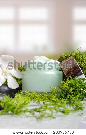 Open cream jar algae. Flowers, black stones and seaweed decoration. Windows background. Front and vertical view