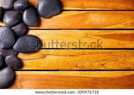 Black stones with water drops in the top left corner on wooden slats. Sauna and massage concept. Horizontal composition. Top view