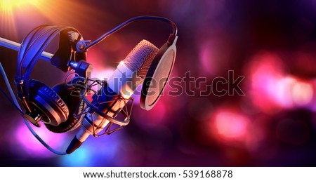 Close up studio condenser microphone with pop filter and anti-vibration mount live recording with color lights background. Side view 商業照片 © 