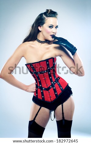 Portrait of a sensuous fashion model in corset standing against colored background