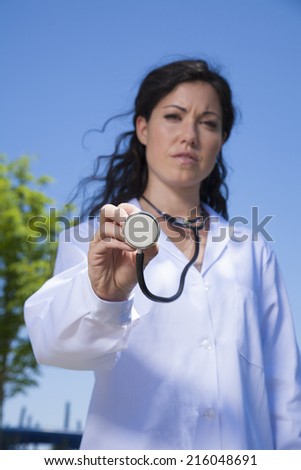 doctor woman showing stethoscope in exterior background